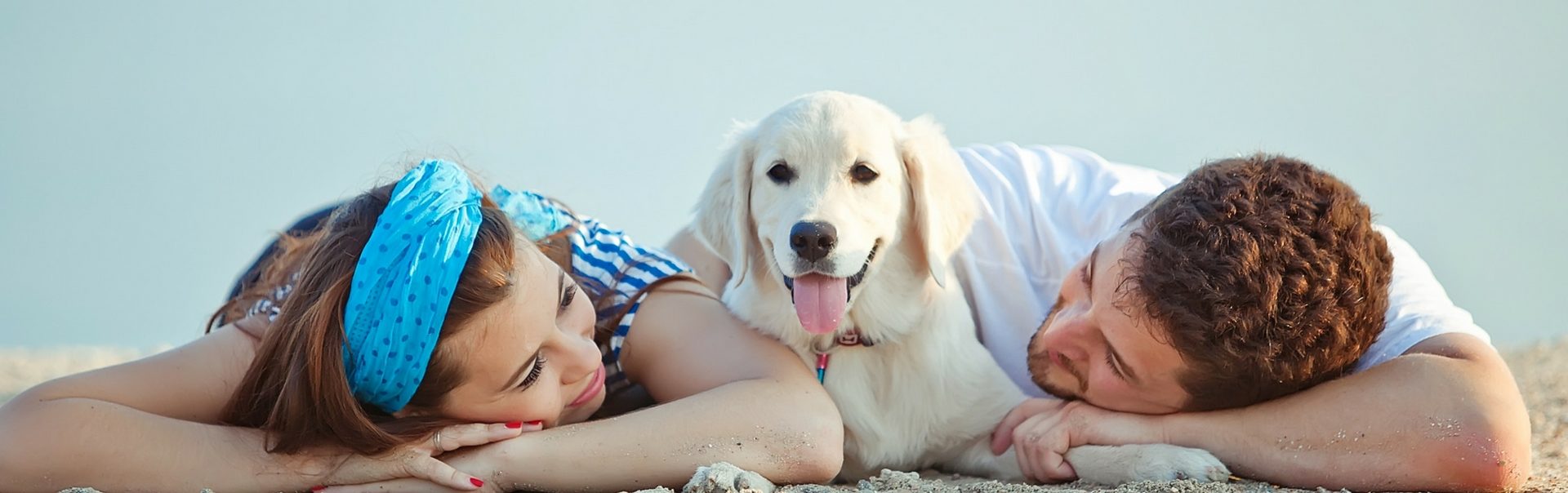 Two people and a dog lying on sand at the beach